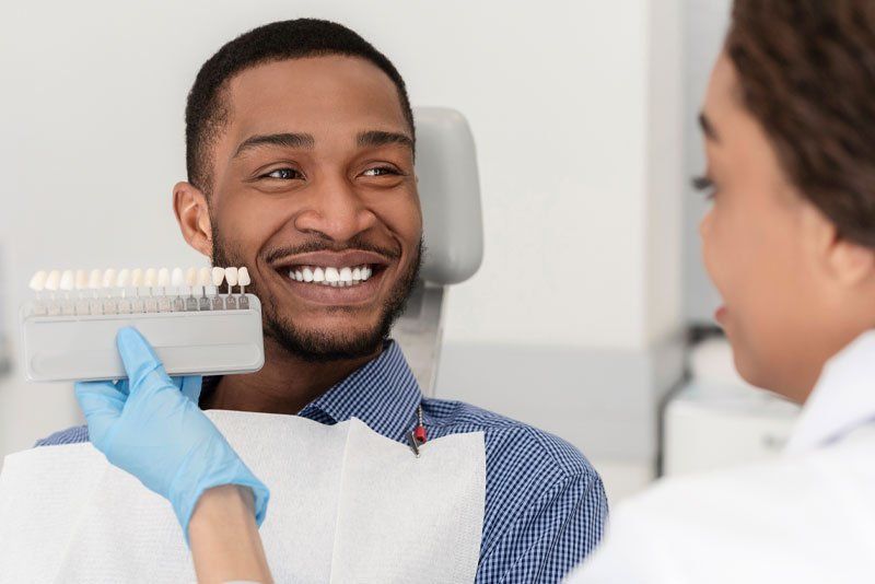 Patient smiling while getting dental crown color matched