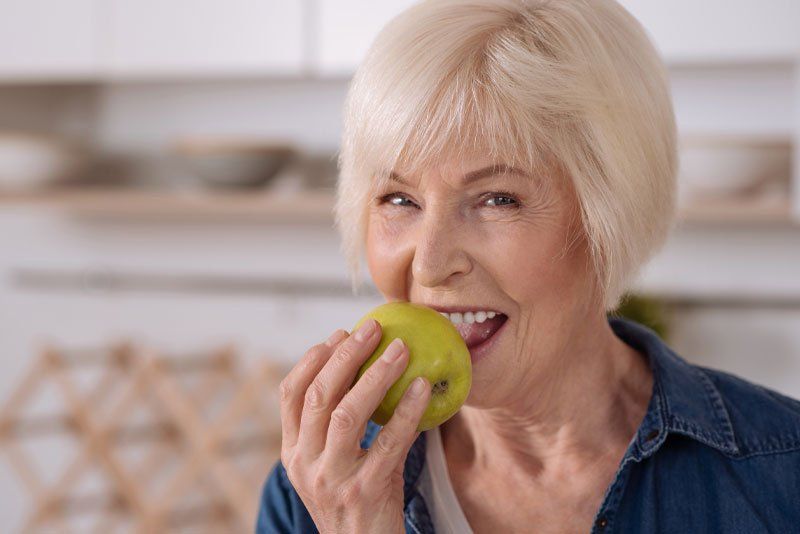 older woman biting into an apple